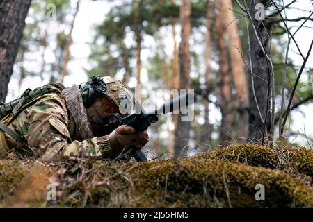 Foto eines Soldaten zielt auf den Feind während eines Zusammenstoßes im Wald. Das Konzept der modernen Kriegsführung und Spezialkräfte. Zugeschnittenes Bild. Stockfoto