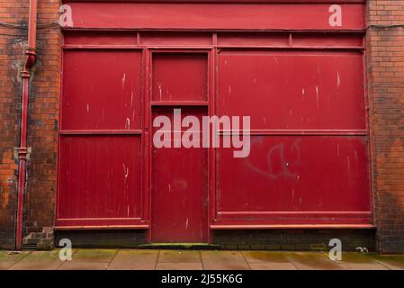 Rote Industrietüren auf einem alten Backsteingebäude in der englischen Stadt. Carlisle, England. Stockfoto