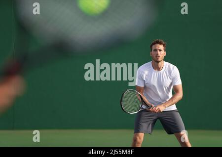 Der Tennisspieler konzentrierte sich darauf, dass andere Spieler mit Schläger auf dem Platz den Ball schlagen. Männer Sport Athleten Spieler spielen Tennis Spiel zusammen. Zwei Profis Stockfoto