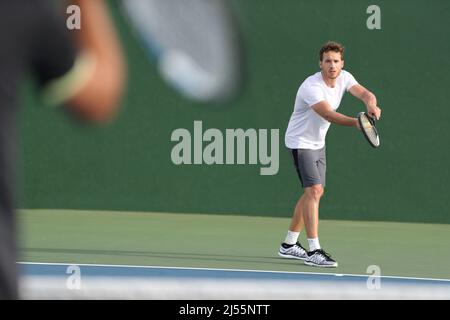 Tennis Serve Spieler Mann serviert Ball während des Spielpunktes auf Outdoor Green Court. Zwei Männer Sportler spielen Sport Spiel Training tun Übung Stockfoto