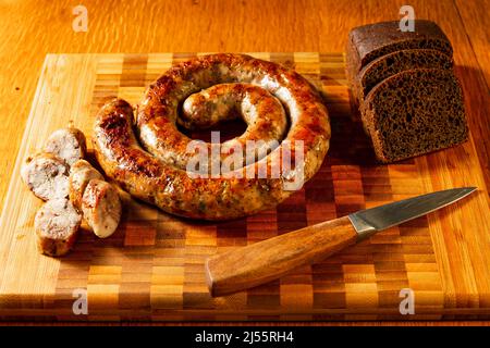 Gegrillte Würstchen auf einem Schneidebrett mit Brot Stockfoto