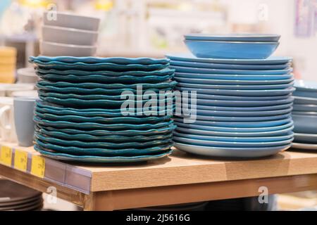 Gerichte werden im Laden verkauft. Reihen von verschiedenen blauen Schalen und Tellern für Zuhause auf Regalen in einem Supermarkt. Stockfoto