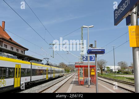 Breisach, Deutschland - April 2022: Bahnhof Breisach, mit Bahnhofschild und Zug an einer der Bahnsteige Stockfoto