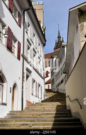 Basel, Schweiz - April 2022: Stufen führen einen Hügel hinauf durch einen kleinen Pfad zwischen alten Gebäuden in der Innenstadt. Keine Personen. Stockfoto