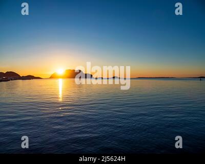 Wunderschöner Sonnenuntergang hinter einer felsigen Insel an der norwegischen Küste Stockfoto