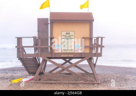 Hölzerner Rettungsschwimmer-Turm mit zwei gelben Fahnen oben gegen den nebligen Strand von San Clemente, CA Stockfoto