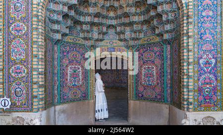 Iran, Shiraz - Mai 2019: Nasir al-Mulk Moschee mit bunten Fliesen und einem Touristen, der sich am Tor lehnt Stockfoto