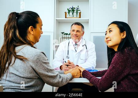 Lächelnde Ärztin und Erwachsene Patientinnen in der Arztpraxis im Gesundheitswesen Stockfoto