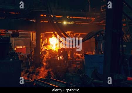 Eisenguss-Prozess in der metallurgischen Fabrik. Geschmolzenes Metall Gießen aus Schöpfkelle in der Werkstatt. Stockfoto