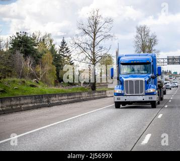 Industriestandard blau Low-Profile-Kabine beladen großen Rig-Sattelschlepper mit Flachbett-Anhänger auf der breiten Autobahn Straße mit Hochspannungs-Leistung Stockfoto