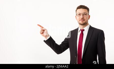 Ein junger Geschäftsmann in einem Geschäftsanzug weist auf Copyspace hin. Stockfoto