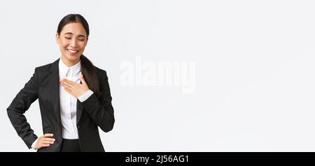 Professionelle erfolgreiche Geschäftsfrau in schwarzem Anzug mit Gespräch, Lachen und berühren Brust als sie etwas lustig oder schmeichelhaft, sein Stockfoto