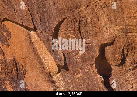 Ein Dickhornschaf spielt Flöte und andere Figuren, die auf der Sand Island Rock Art Panel am San Juan River in Utah dargestellt sind. Es ist eine große Sammlung Stockfoto