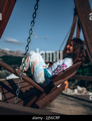 Frau, die Berge auf der Schaukel sitzend beobachtet Stockfoto