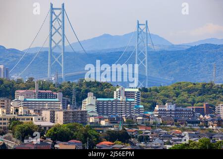 Die Hängebrücke ragt hoch über weitläufige Vororte und Wohnblocks Stockfoto