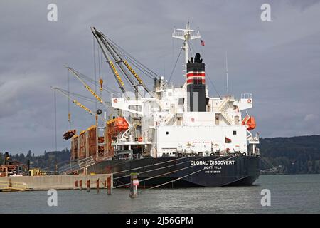 Die Global Discovery, ein in Vanuatu registriertes „Bulk Carrier“-Schiff, an den Docks in Coos Bay, Oregon, lädt Tausende von Tonnen Halm- und Tannenholz aus dem Pazifischen Nordwesten nach Hiroshima, Japan. Stockfoto