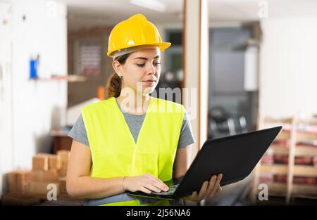 Bauarbeiterin mit Laptop in der Wohnung Stockfoto