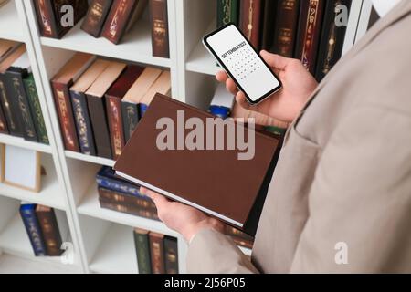 Mann mit Notebook und modernem Mobiltelefon mit Kalenderanwendung im Büro Stockfoto