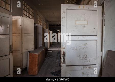 Bild eines beschädigten Innenraums eines verlassenen Bürogebäudes mit einem Raum voller Staub, Müll und einem verbleibenden Schreibtisch. Stockfoto