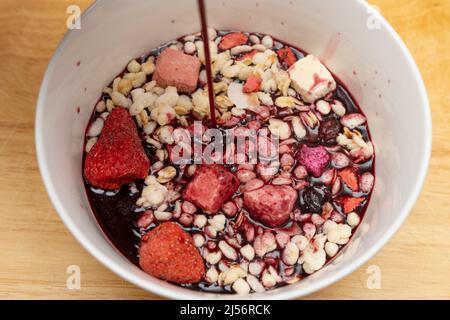 Gießen Sie Maulbeersaft in eine Schüssel mit Nüssen und trockenen Früchten und Melonensamen Stockfoto