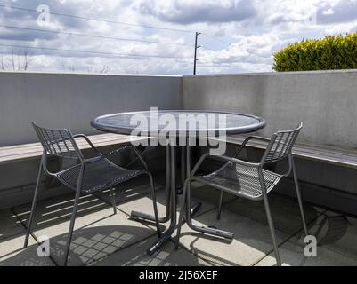 Blick auf einen Dachbalkon mit einem runden Metalltisch und zwei Stühlen und Blick auf die Innenstadt von Bellevue, WA Stockfoto