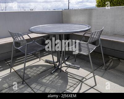 Blick auf einen Dachbalkon mit einem runden Metalltisch und zwei Stühlen und Blick auf die Innenstadt von Bellevue, WA Stockfoto