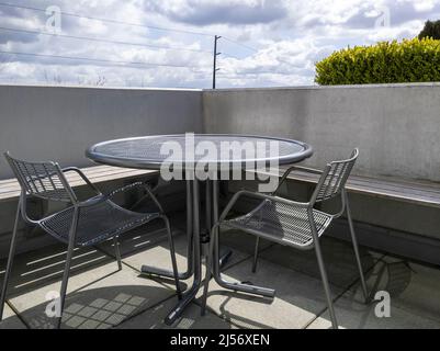 Blick auf einen Dachbalkon mit einem runden Metalltisch und zwei Stühlen und Blick auf die Innenstadt von Bellevue, WA Stockfoto