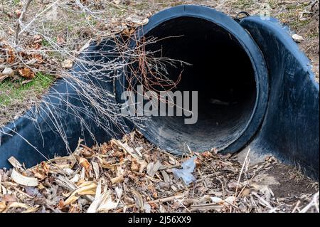 HDPE-Drainage unter einer Straßeneinfahrt. Das Rohr dient zur Förderung von Regenwasser zwischen Gräben. Stockfoto