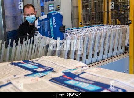 Ulm, Deutschland. 20. April 2022. Steffen Tietze platziert Papiertüten während der Produktion bei Uzin Utz in eine Abfülllinie. Der börsennotierte Baustoffhersteller stellt auf einer Jahrespressekonferenz am 21. April 2022 die Zahlen des Unternehmens für das vergangene Geschäftsjahr vor. Quelle: Stefan Puchner/dpa/Alamy Live News Stockfoto