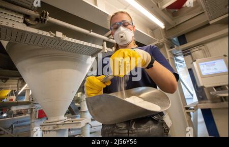 Ulm, Deutschland. 20. April 2022. Cora Kuttmann, Chemikerin, lässt bei Uzin Utz ein Pulver durch ihre Hand in eine Rutsche tröpfeln. Der börsennotierte Baustoffhersteller stellt auf einer Jahrespressekonferenz am 21. April 2022 die Zahlen des Unternehmens für das vergangene Geschäftsjahr vor. Quelle: Stefan Puchner/dpa/Alamy Live News Stockfoto