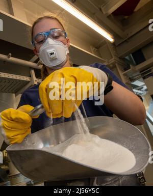 Ulm, Deutschland. 20. April 2022. Cora Kuttmann, Chemikerin, lässt bei Uzin Utz ein Pulver durch ihre Hand in eine Rutsche tröpfeln. Der börsennotierte Baustoffhersteller stellt auf einer Jahrespressekonferenz am 21. April 2022 die Zahlen des Unternehmens für das vergangene Geschäftsjahr vor. Quelle: Stefan Puchner/dpa/Alamy Live News Stockfoto