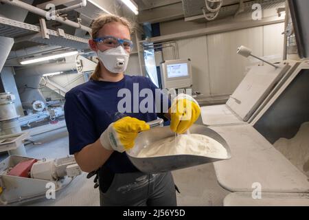 Ulm, Deutschland. 20. April 2022. Cora Kuttmann, Chemikerin, lässt bei Uzin Utz ein Pulver durch ihre Hand in eine Rutsche tröpfeln. Der börsennotierte Baustoffhersteller stellt auf einer Jahrespressekonferenz am 21. April 2022 die Zahlen des Unternehmens für das vergangene Geschäftsjahr vor. Quelle: Stefan Puchner/dpa/Alamy Live News Stockfoto