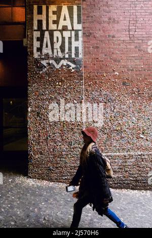 Seattle, USA. 20. April 2022. Eine Person, die an der berühmten Gummimauer in der Post Alley vorbeikommt. Stockfoto