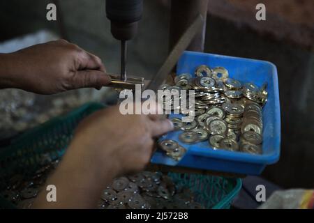 Herstellung traditioneller balinesischer Münzen mit hohlem Namen "pis bolong/jinah bolong/uang kepeng" in Kamasan, Klungkung, Bali, Indonesien. Die Münzen, die in der Vergangenheit bei Transaktionen auf Bali verwendet wurden, sind heute in traditionellen religiösen Ritualen auf der 'Insel der Götter' unverzichtbar. Stockfoto