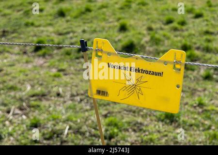 schild Gefahr an einem elektrischen Zaun auf einer Wiese Stockfoto