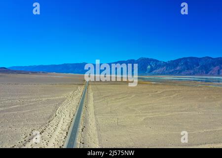 Wüstenlandschaft mit braun-orangefarbenem Sand und Landstraße. Panamint Valley in der Nähe von Furnace Creek. Death Valley National Park Stockfoto