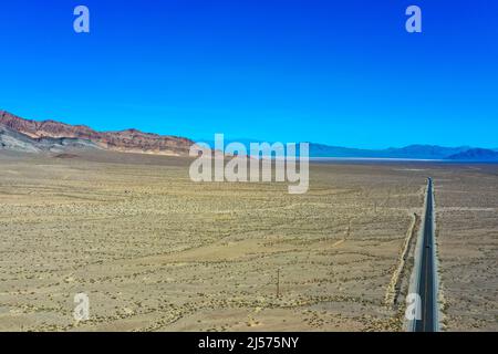 Wüstenlandschaft mit braun-orangefarbenem Sand und Landstraße. Panamint Valley in der Nähe von Furnace Creek. Death Valley National Park Stockfoto