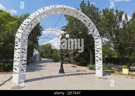 Jewpatoria, Krim, Russland - 25. Juli 2021: Der weiße Bogen am Eingang zum Garten, der nach Lenin in der Stadt Jewpatoria, Krim benannt ist Stockfoto