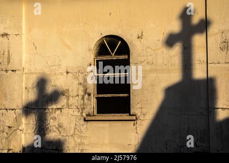 Schatten von Kreuzen an der Wand einer alten Kapelle auf einem Friedhof in Brasilien Stockfoto