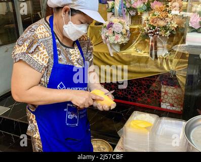 Bangkok, Thailand. 20. April 2022. Eine Frau bereitet an einem Straßenstand im Distrikt Silom Mango Sticky Rig zu. Die thailändische Regierung möchte vielleicht das beliebte Dessert für die UNESCO-Welterbeliste vorschlagen. (To dpa 'Thai Rapper löst Hype aus: 'Mango Sticky Reis' als Welterbe?') Quelle: Carola Frentzen/dpa/Alamy Live News Stockfoto