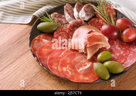 Nahaufnahme von verschiedenen Fleischsnacks, Wurstplatte mit verschiedenen Wurstsorten - Salami, bresaola, Proscuitto serviert mit Oliven, rosig Stockfoto