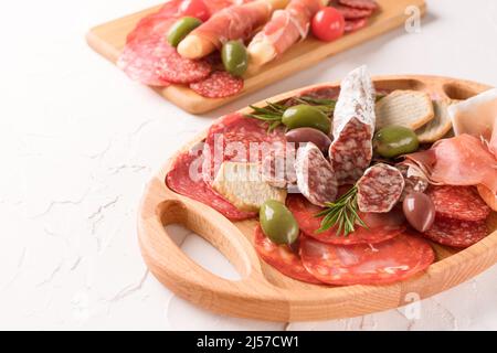 Wurstplatte mit verschiedenen Arten von Fleisch Snacks - Salami, Bresaola, Proscuitto serviert mit Oliven, Rosmarin und Cracker. Holzplatten mit tra Stockfoto