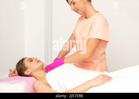 Kosmetikerin mit einem Patienten während der Zuckerzuckerung. Der Kosmetologe wachse die weibliche Achselhöhle Stockfoto