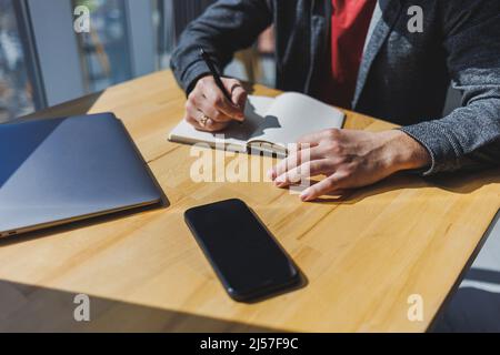 Nahaufnahme der männlichen Hände eines Geschäftsmannes mit einem Notizblock und einem Stift Stockfoto