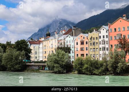 Innsbruck vom Inn aus mit bunten Gebäuden und Bergen am wolkigen Sommertag. Schöne Architektur der Alpenstadt in Tirol. Stockfoto