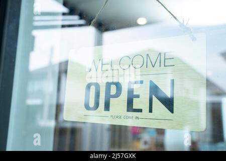 An der Glastür hängt ein Schild mit der Aufschrift „Öffnen“ Stockfoto