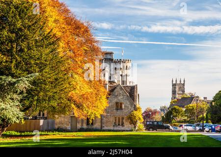 Wunderschöne Herbstfarben im Cirencester Park auf dem Bathhurst Estate in Gloucestershire. Der Turm der Kirche von Johannes dem Täufer und ein Teil der Stockfoto