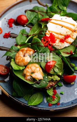 Das Buchweizenbrot wird mit einem pochierten Ei, einer in Scheiben geschnittenen Avocado, Garnelen, Tomaten und Salat geröstelt. Diätmenü. Flach liegend Stockfoto