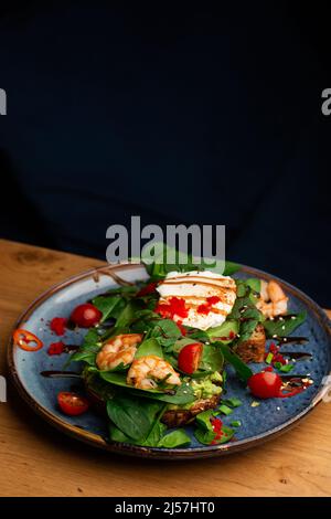 Das Buchweizenbrot wird mit einem pochierten Ei, einer in Scheiben geschnittenen Avocado, Garnelen, Tomaten und Salat geröstelt. Diätmenü. Flach liegend Stockfoto