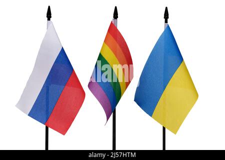 Nahaufnahme von drei Fahnenmasten mit ukrainisch-russischer Flagge und dazwischen Regenbogenfahne auf weißem Hintergrund als Konzept für den Frieden in Osteuropa Stockfoto